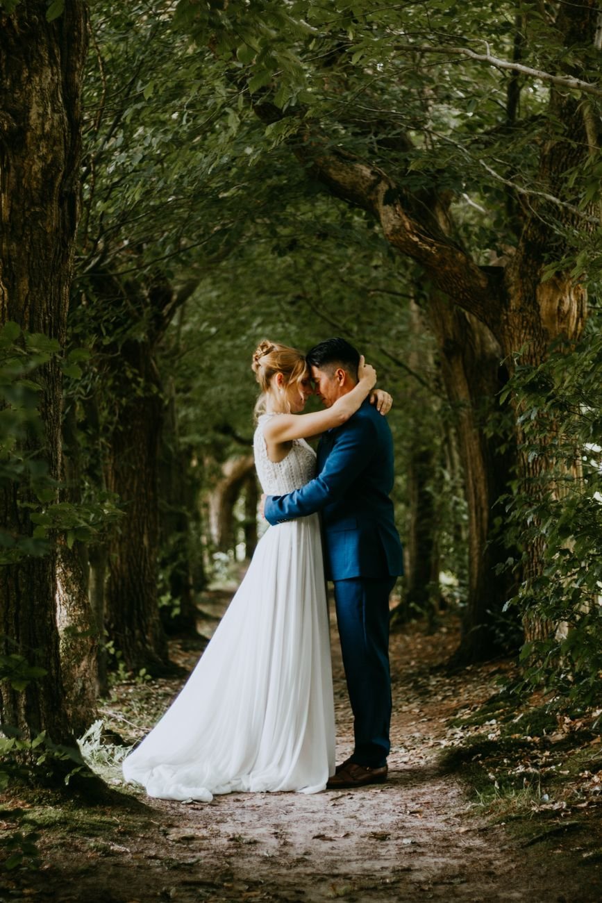 Couple embracing in a lush forest tunnel, celebrating their outdoor wedding.
